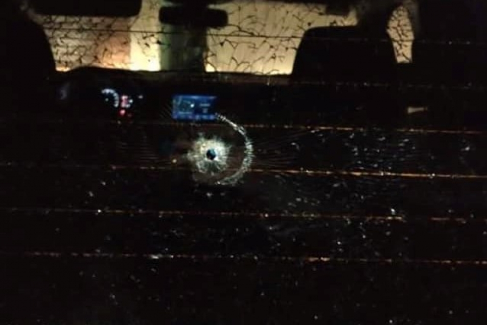 La luneta de un vehículo perforada por el proyectil. 