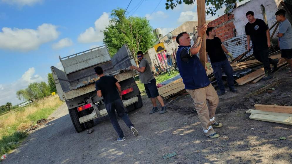 Municipales, descargando tirantes y chapas en una casa afectada.