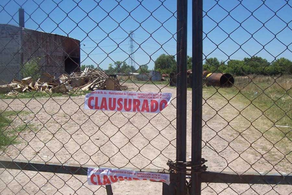 Las fajas de clausura puestas en el portón de ingreso al predio. 