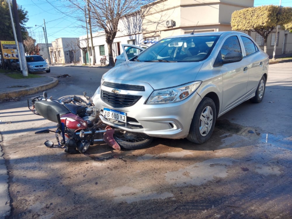 La moto tumbada debajo del Chevrolet. 